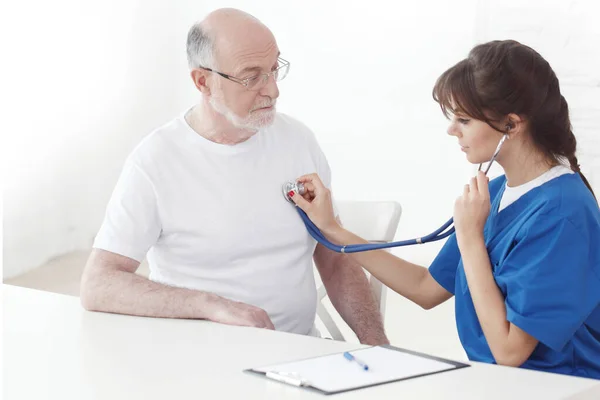 Doktor yaşlı adamın kalp atışlarını dinliyor. — Stok fotoğraf