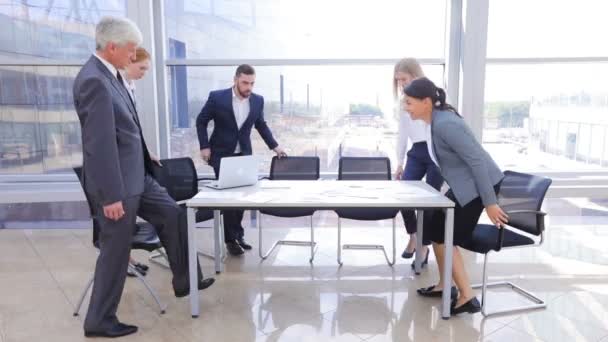 テーブルに座ってノートパソコンやオフィスの書類を扱うビジネスチーム — ストック動画