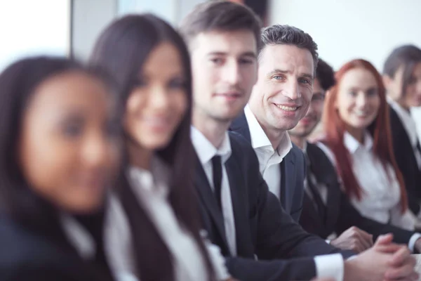 会議や笑顔でデスクに座って列に成功したビジネスの人々グループ — ストック写真