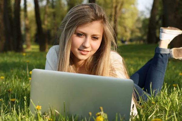 Kız parkta dizüstü bilgisayarla çalışıyor.