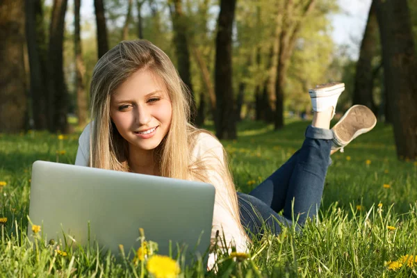 Kız parkta dizüstü bilgisayarla çalışıyor.
