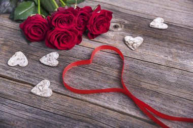 Kırmızı gül ve kalp ahşap arka plan üzerinde.