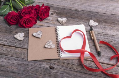 Defter ve gül ahşap arka plan üzerinde.