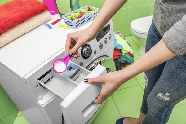 Woman throws laundry detergent into the washing machine. — Stock Photo, Image