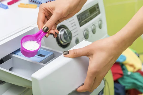 Mulher joga detergente de roupa na máquina de lavar roupa . — Fotografia de Stock