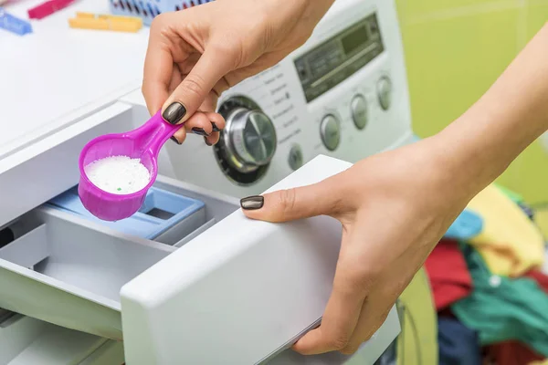 Kadın çamaşır deterjanı çamaşır makinesi atar..