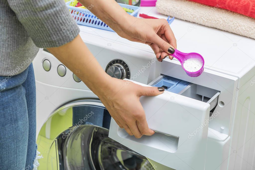 Woman throws laundry detergent into the washing machine.