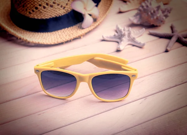 Cappello di paglia e occhiali da sole su tavole di legno . — Foto Stock