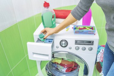 Hand pours liquid powder into the washing machine. clipart