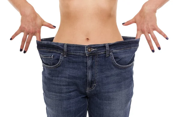 La mujer demuestra que ha perdido peso. Pantalones vaqueros . — Foto de Stock