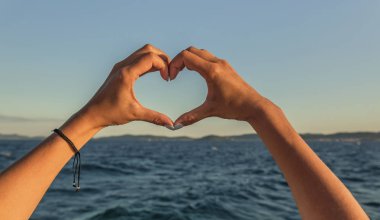Deniz arka planı kalp şeklinde el.