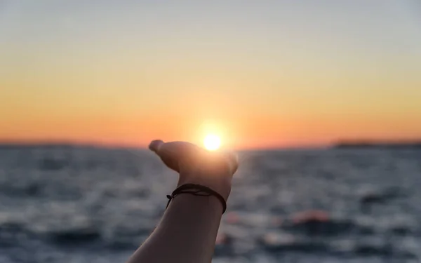 Hand greift nach der Sonne bei Sonnenuntergang. — Stockfoto