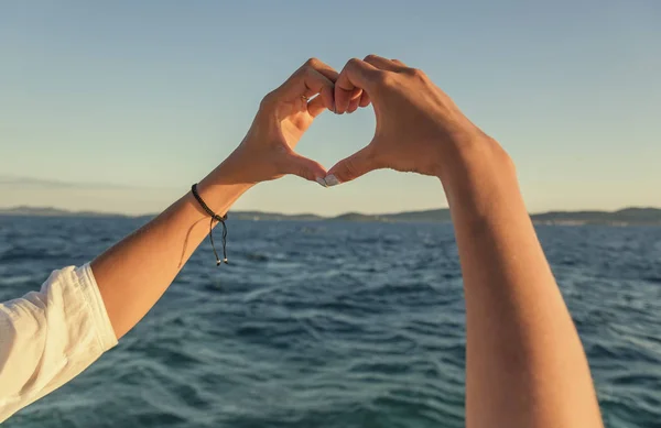 Hände in Herzform vor dem Hintergrund des Meeres. — Stockfoto