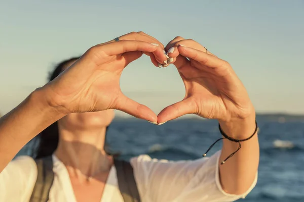 Hands in the shape of heart against the background of the sea. — Stock Photo, Image
