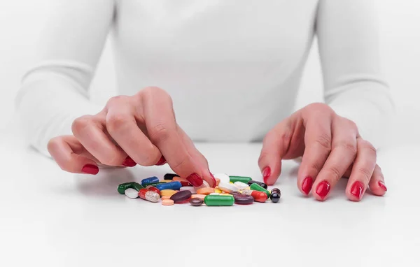 Woman chooses medicine from a handful of different color tablets. — Stock Photo, Image