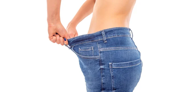 Slender girl in big jeans on a white background. Losing weight. — Stock Photo, Image