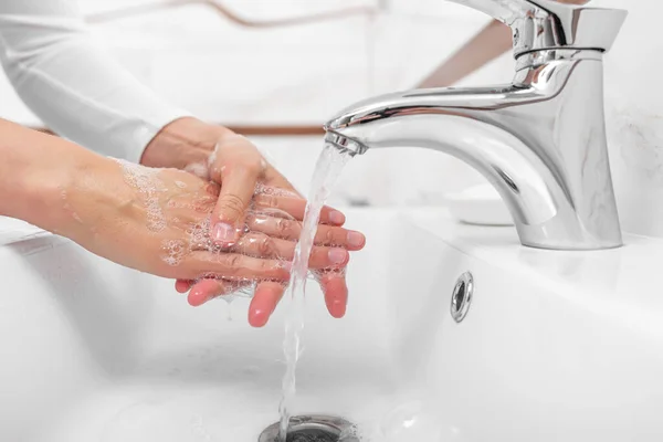 Кто-то моет руки с мылом, стоя в ванной. . — стоковое фото