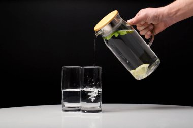 Two glasses and jar of water on dark background