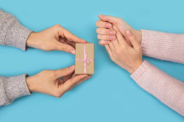 Kadın el gider için mavi arka plan yandan mans. Mens elleri küçük bir hediye bir kadına verdin..