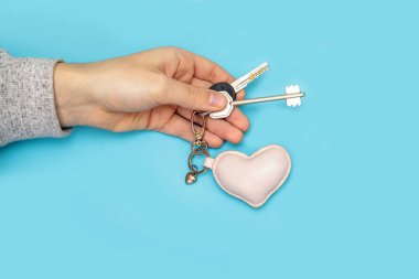 Yeni bir anahtar tutan dışarı adam kol. Mens eller mavi bir arka plan üzerinde anahtarları ver.