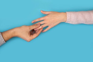 Adam onun kız evlenmek için bir teklif yapar. Mens yüzük kızlar yandan ellerini. Mavi bir arka plan üzerinde bir halka ile erkek ve dişi eller.