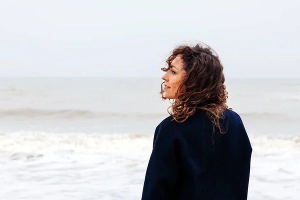 Девушка дождя морской ветер зимний портрет женщина улыбка весеннее пальто длинные волосы кудрявое настроение берега снежного пляжа — стоковое фото
