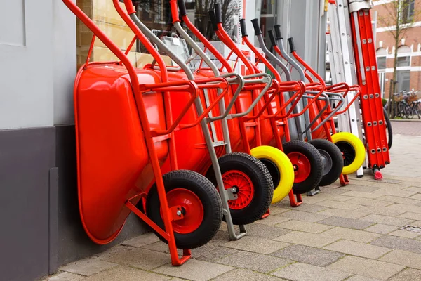 Kırmızı arabaları üst üste Satılık dur. Yeni bahçe el arabası ile sarı ve siyah tekerlek.