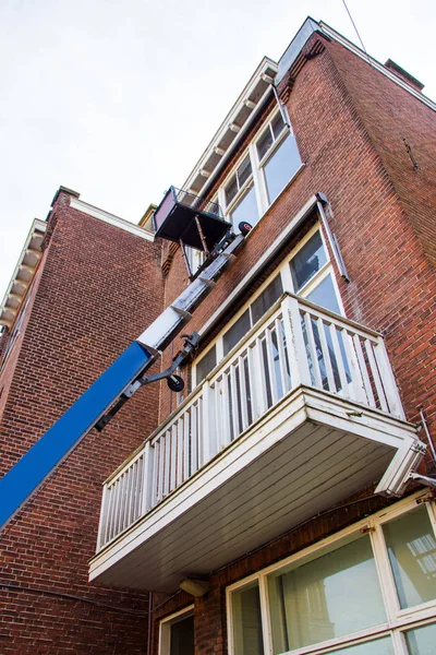 The Used blue Boom Lifts for repair and washing windows. Lift on the background of an old brick house with a window.