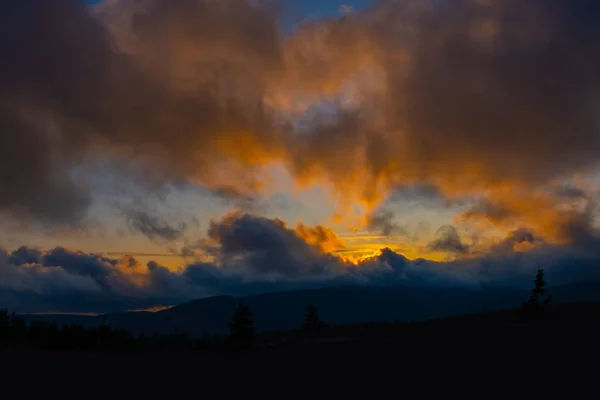 Puesta de sol montaña cielo azul colorido otoño sol luz amarillo naranja nubes árbol humo niebla neblina — Foto de Stock