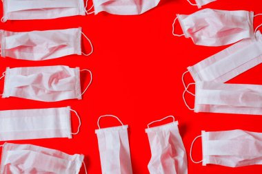 Kırmızı arka planda tıbbi maske var. Bir sürü maske. en üstteki görünüm.