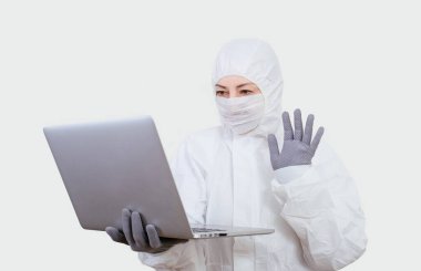 Koruyucu takım elbiseli ve yüz maskesi takan kadın doktor internet üzerinden. Beyaz arka planda not defteri olan sağlık görevlisi kadın..