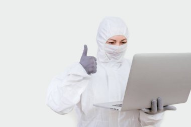 Koruyucu takım elbiseli ve yüz maskesi takan kadın doktor internet üzerinden. Beyaz arka planda not defteri olan sağlık görevlisi kadın..