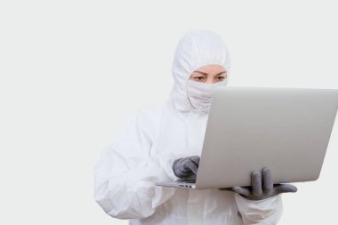 Koruyucu takım elbiseli ve yüz maskesi takan kadın doktor internet üzerinden. Beyaz arka planda not defteri olan sağlık görevlisi kadın..