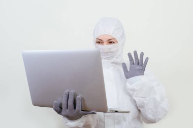 Koruyucu takım elbiseli ve yüz maskesi takan kadın doktor internet üzerinden. Beyaz arka planda not defteri olan sağlık görevlisi kadın..