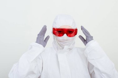 Koruyucu giysili kadın doktor, yüz maskesi ve kırmızı gözlük. Sağlık görevlisi beyaz arka plandaki kadını üzdü.