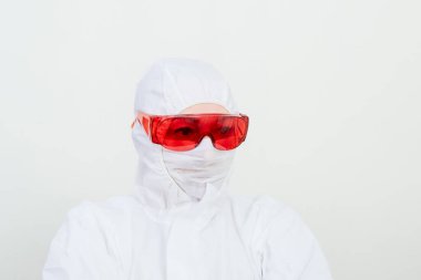 Koruyucu giysili kadın doktor, yüz maskesi ve kırmızı gözlük. Sağlık görevlisi beyaz arka plandaki kadını üzdü.