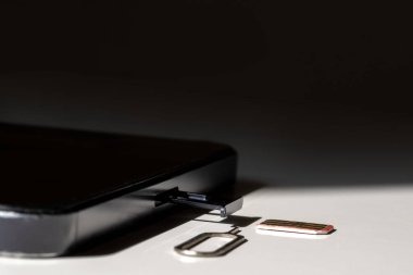 Beyaz arkaplanda SIM kart, telefon ve yuva, kopyalama alanı, üst görünüm.