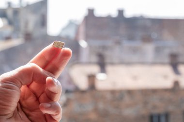 Sokakta üzerinde gökyüzü ve evler olan bir SIM kart tutuyor, boşluğu kopyala.
