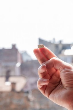 Sokakta üzerinde gökyüzü ve evler olan bir SIM kart tutuyor, boşluğu kopyala.