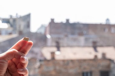 Sokakta üzerinde gökyüzü ve evler olan bir SIM kart tutuyor, boşluğu kopyala.