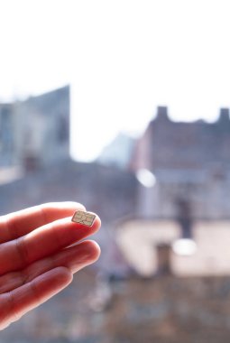 Sokakta üzerinde gökyüzü ve evler olan bir SIM kart tutuyor, boşluğu kopyala.