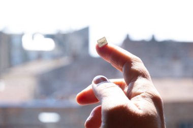 Sokakta üzerinde gökyüzü ve evler olan bir SIM kart tutuyor, boşluğu kopyala.