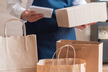 Bir sürü kağıt torba ve kutu Packer 'ın yanında kalıyor. Müşteri Teslimat Hizmeti Paketleme Emri.