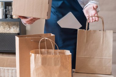 Bir sürü kağıt torba ve kutu Packer 'ın yanında kalıyor. Müşteri Teslimat Hizmeti Paketleme Emri.