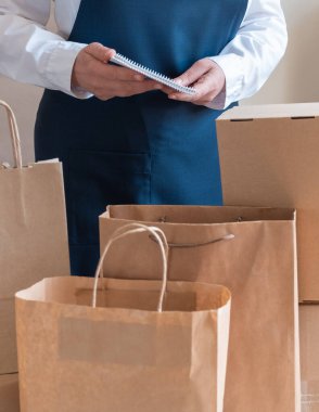 Bir sürü kağıt torba ve kutu Packer 'ın yanında kalıyor. Müşteri Teslimat Hizmeti Paketleme Emri.