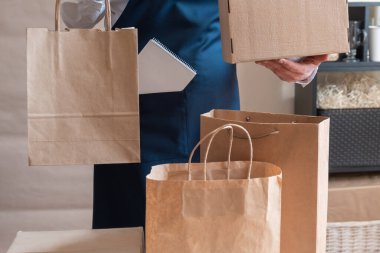 Bir sürü kağıt torba ve kutu Packer 'ın yanında kalıyor. Müşteri Teslimat Hizmeti Paketleme Emri.