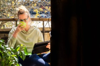 Kıdemli kadın sabahları terasında dışarıda çalışıyor. Orta Çağ Kadını, Balkon ve Kullanım Aygıtı 'nda oturuyor.