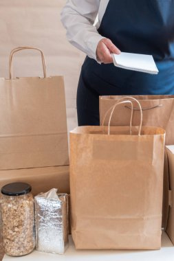 Bir sürü kağıt torba ve kutu Packer 'ın yanında kalıyor. Müşteri için Üniformalı Paketleme Hizmeti Teslimat Servisi.