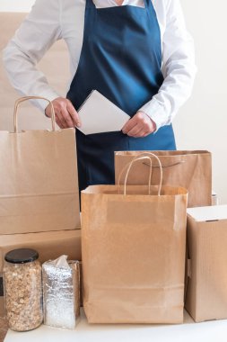 Bir sürü kağıt torba ve kutu Packer 'ın yanında kalıyor. Müşteri için Üniformalı Paketleme Hizmeti Teslimat Servisi.