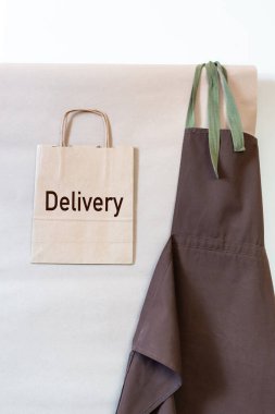 Kağıt poşetlerde tabela teslimat ve duvarda kahverengi önlük var. Müşteri için Üniforma Teslimat Servisi.